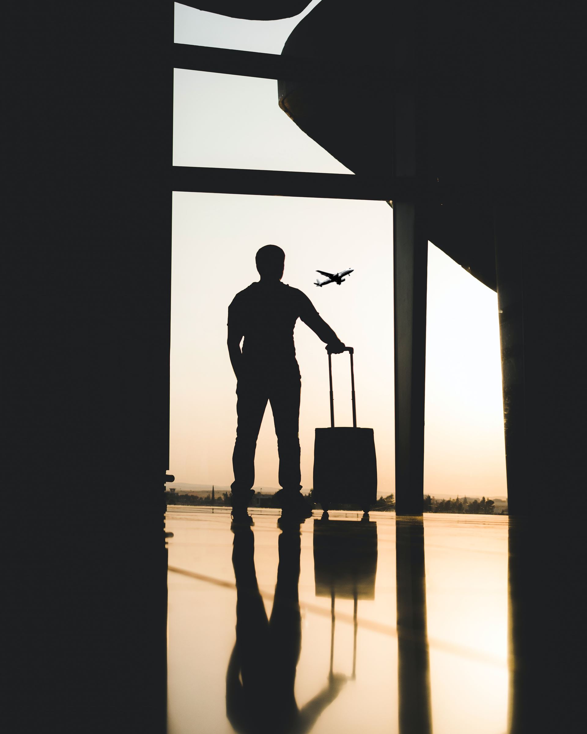 a silhouette of a man at the airport with a suitcase