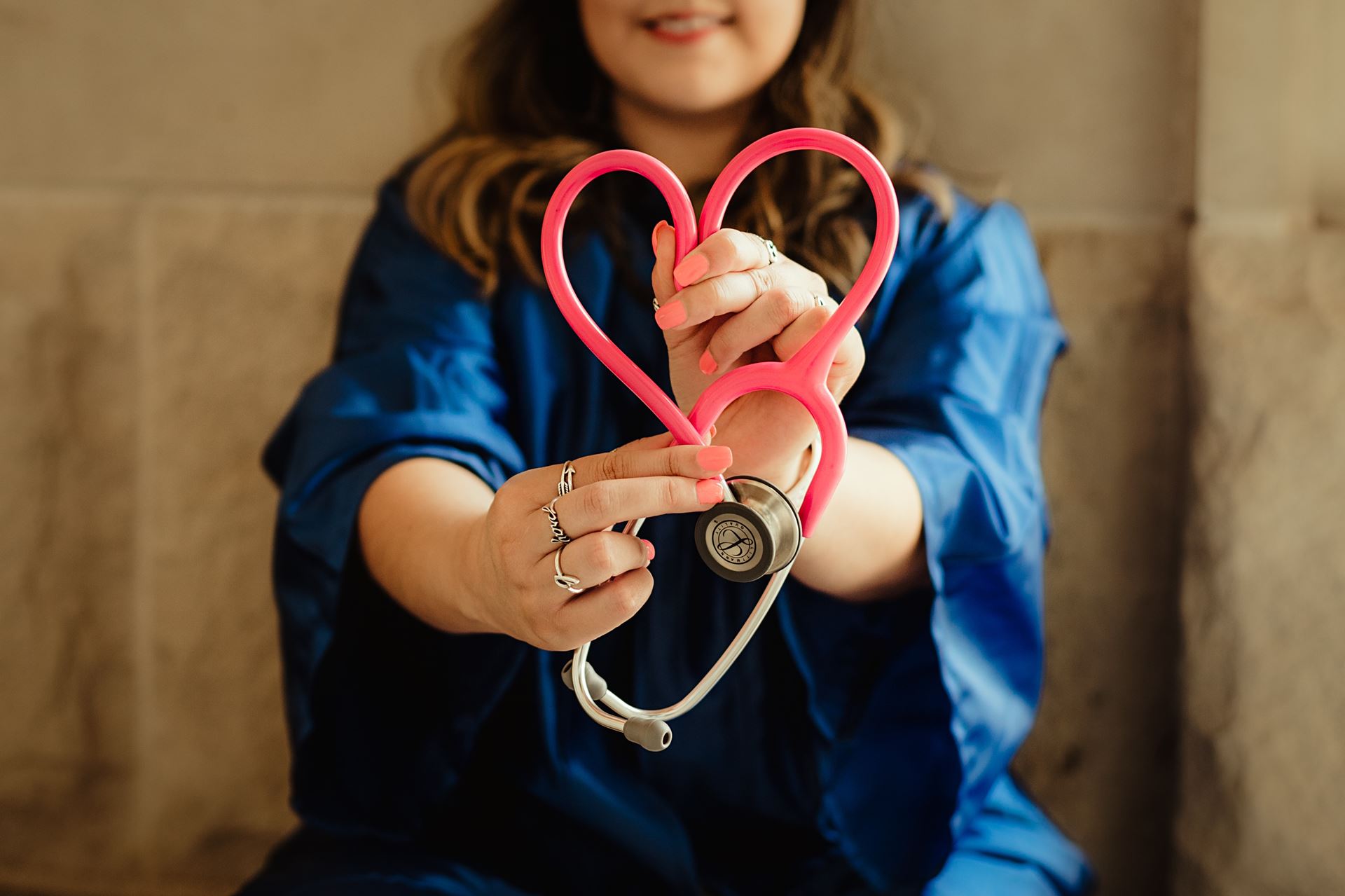 a healthcare progessional holding a stethscope shaped like a heart