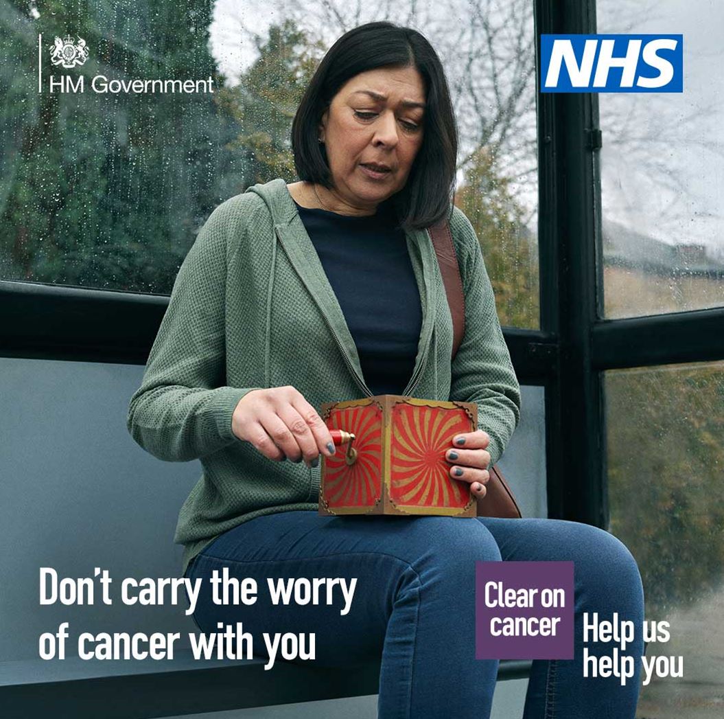 a woman sat at a bus stop holding a windup music box, the NHS logo and the words don't carry the worry of cancer with you.  Clear on cancel.  Help us,  help you. 